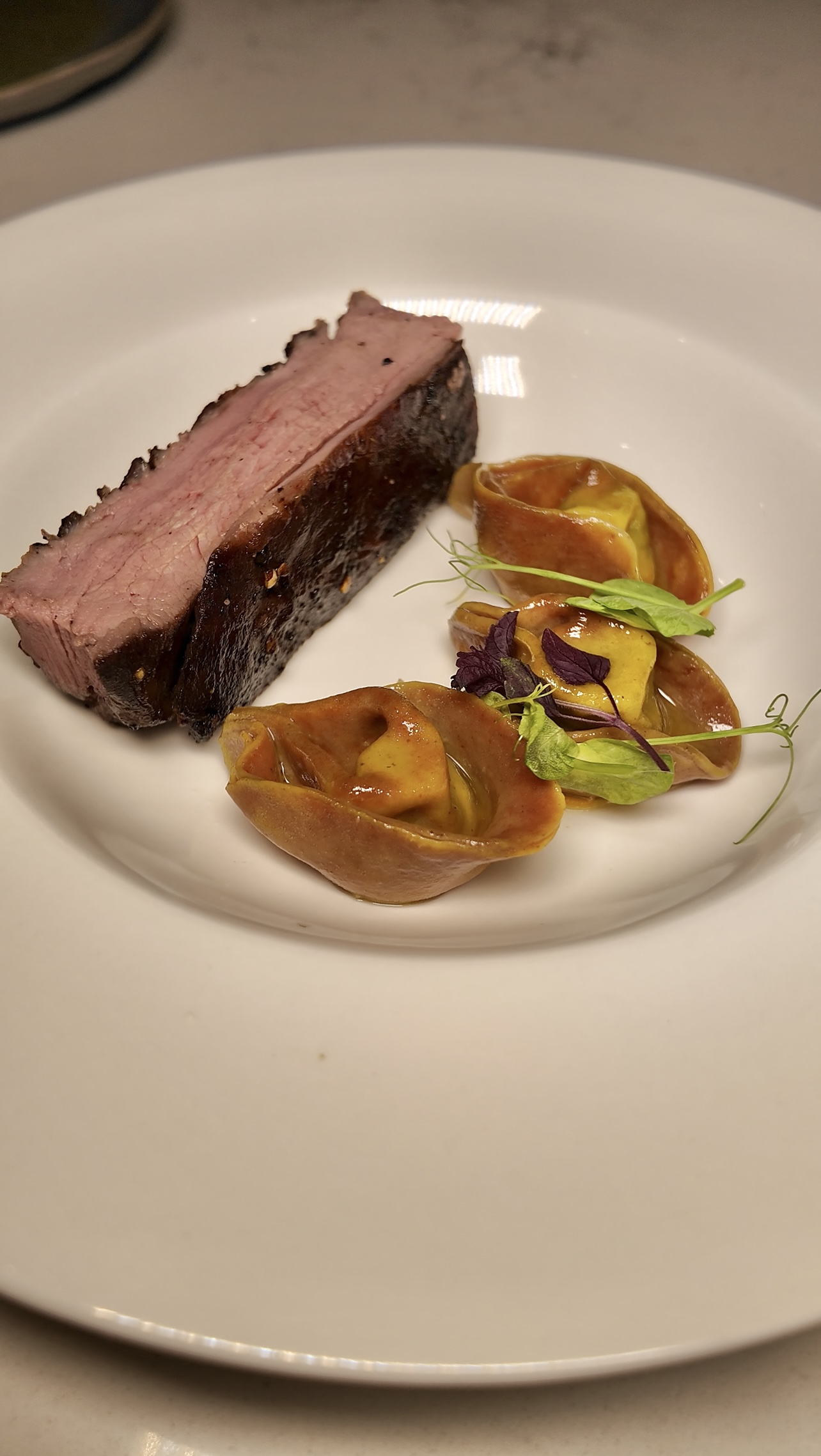 Seared beef with tortellini and pea shoots