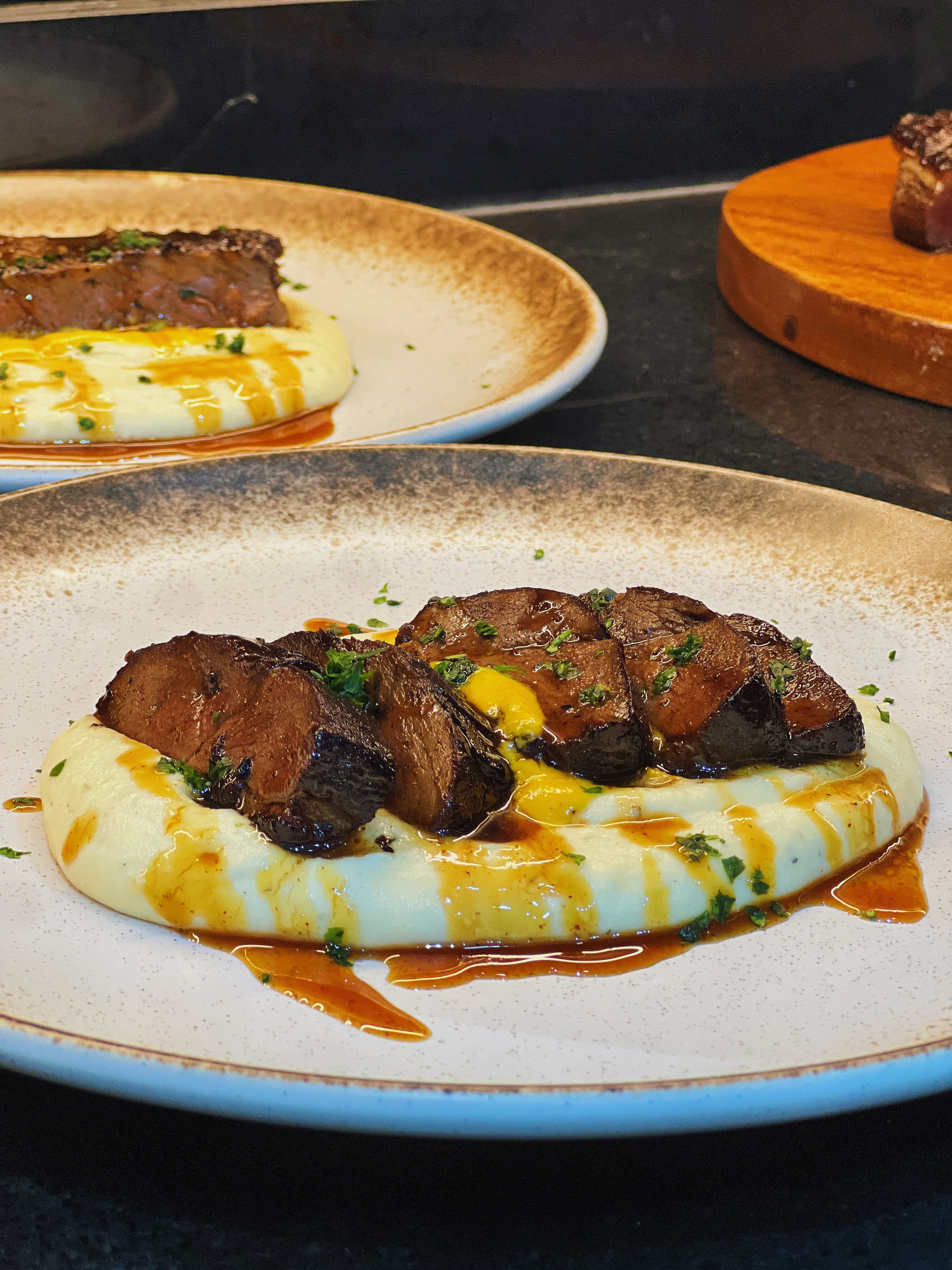 Sliced glazed meat on mash with jus